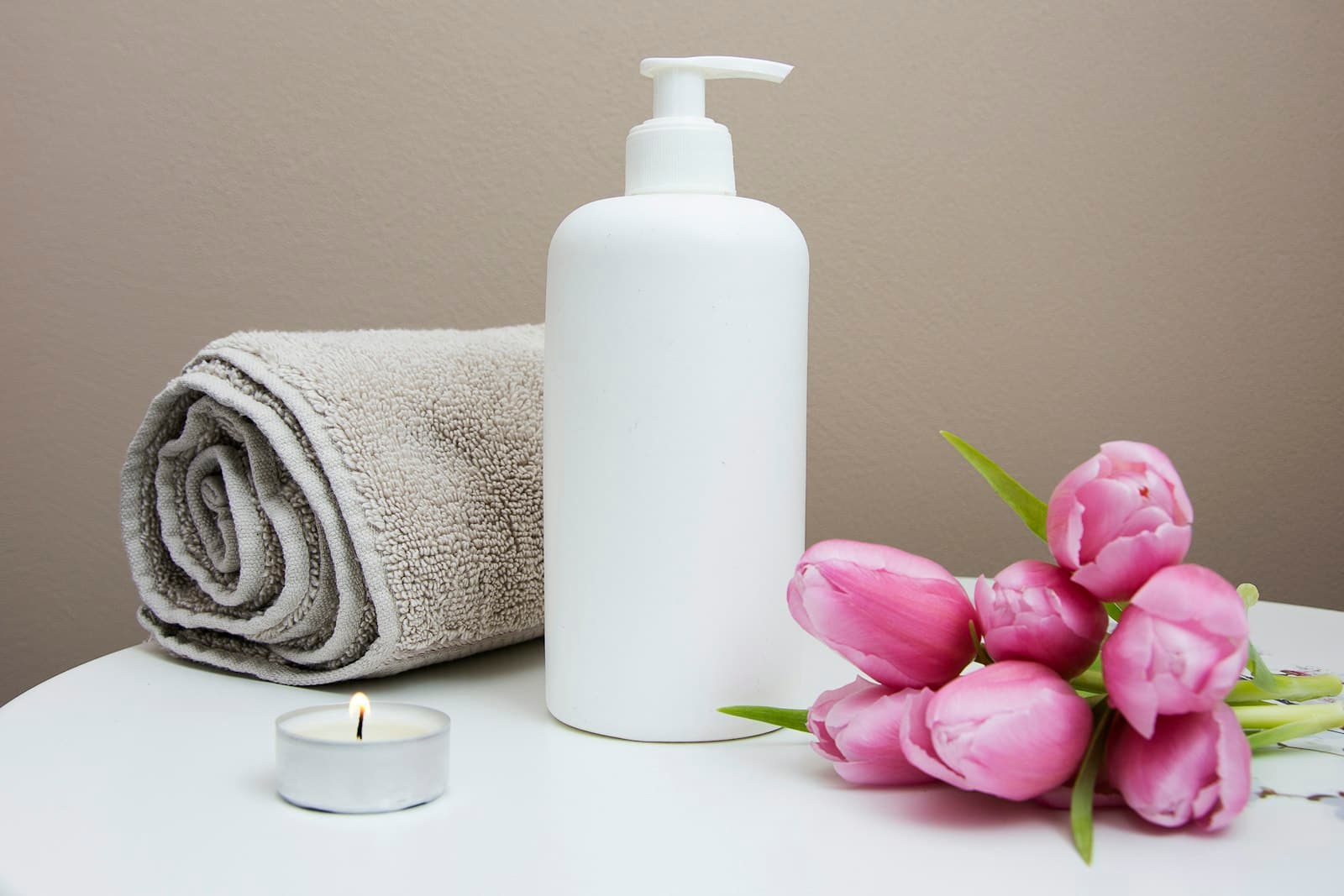 Rolled towel, candle, and pink tulips in a treatment room